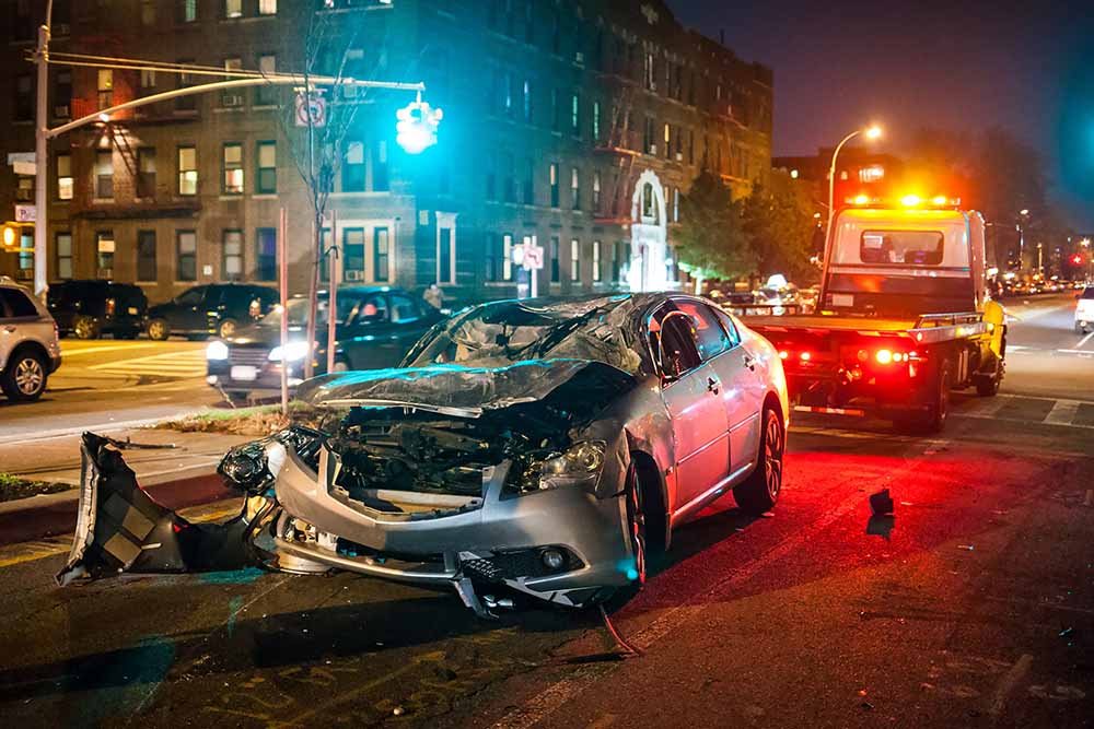 A heavily damaged car being hooked up to a tow truck